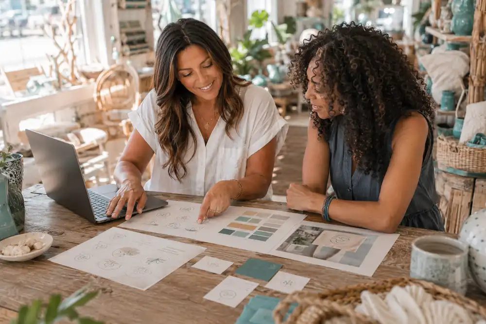 Local designer and a small-business owner reviewing brand concepts together at a studio table