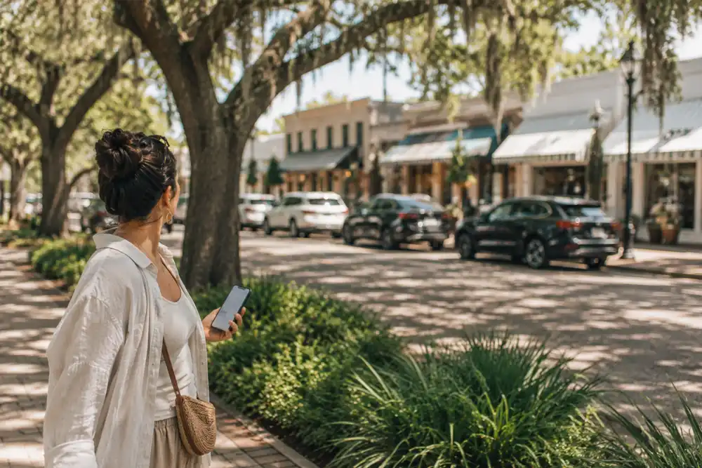 Visitor comparing local businesses on a phone on a St. Simons Island street
